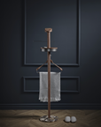 Wooden coat rack with a towel against a dark wall