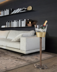 Modern living room with a white sofa, decorative shelves, and a gold ice bucket with a bottle.