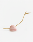 Pink quartz with a gold branch of birds of paradise flower on a white background