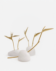 Decorative arrangement with gold bird of paradise flowers on white quartz against a light gray background
