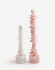 A pair of table top pink quartz and white quartz totem sculpture on a white background
