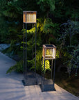 Two solar-powered outdoor floor and table lamps on a patio with greenery in the background by Les Jardins available at Spacio retail stores in Mumbai & Kolkata.