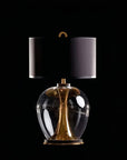 Table lamp with black shade and gold base on a black background from Pieter Adam available at Spacio in India.