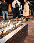 People gathered around a fire pit on a brick patio with a building in the background