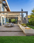 Modern outdoor patio with a fire pit, chairs, and a view of a house.
