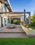 Modern outdoor patio with a fire pit, chairs, and a view of a house.