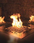 Glass fireplace insert with flames burning inside a stone fireplace.