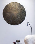 Decorative circular wall art on a white wall with a lamp and textured surface in the foreground by Gardeco available at Spacio retail stores in Mumbai & Kolkata.
