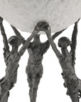 Bronze sculpture of three figures holding up a large sphere on a white background