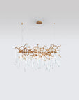 A Serip Aqua Chandelier, a nature-inspired gold chandelier with crystal drops hanging from it.