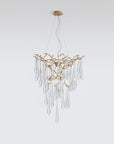 A Serip Aqua Chandelier from the Serip brand, crafted with gold and crystal materials, hangs elegantly from a white wall.