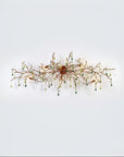 A wall light with Glass shaped falling droplets of water hanging from gold colour branches