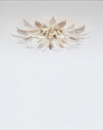 A flower shaped light with glass and metal fixed on the ceiling on a light grey colour background