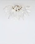 A flower shaped ceiling light in glass and metal fixed on the ceiling on alight grey colour background