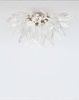 A flower shaped ceiling light in glass and metal fixed on the ceiling on alight grey colour background