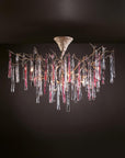 A colourful chandelier suspended from a ceiling with colourful glass icicles hanging from golden colour branches on a dark grey background.