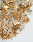 Close up of decorative sculptural wall lights with leaves in gold and silver on a white background