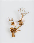 Decorative wall sconce with gold branches and leaves on a light blue background