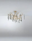 A chandelier suspended from a ceiling with colourful glass icicles hanging from golden colour branches on a dark grey background.
