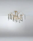 A chandelier suspended from a ceiling with colourful glass icicles hanging from golden colour branches on a dark grey background.