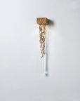 Decorative wall light with gold branches and crystal shaped like a water drop on a white background