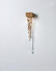 Decorative wall light with gold branches and crystal shaped like a water drop on a white background