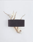 Wall-mounted light fixture with dark gray shade and branch-like design with a white bird on a white background