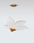 Decorative sculptural hanging light in leaf shape made of brass and glass with gold accents on a white background