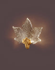 Decorative leaf-shaped wall light with gold base on a dark background