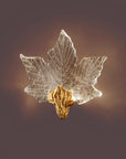 Decorative leaf-shaped wall light with gold base on a dark background