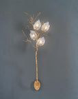 Decorative wall light fixture with gold branch and glass shades on a dark gray background