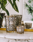 Decorative glass candles with intricate designs on a marble surface.