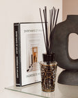 A Baobab Arabian Nights Diffuser with a woody fragrance graces a shelf alongside a book available at Spacio India for luxury home decor collection of Candles & Frangrace.