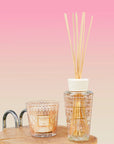 A Baobab Paris My First Baobab TOTEMMSSI fragrance diffuser on a wooden table next to a glass.