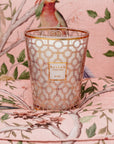 A Baobab Women Candle MAX16WOM sitting on a pink chair, symbolizing support for the Breast Cancer Foundation and women's health, with delicate bird designs.