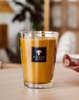 A Baobab Zanzibar Candle Max 16MAX16AZS, infused with the fragrance of Zanzibar Spices, is sitting on a wooden table.