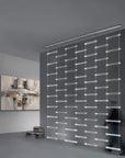 A man walks through a room with an Italamp Piola lighting fixture made of cast glass bars.