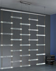 A room with a Italamp Piola lighting fixture hanging from the ceiling, featuring Italamp and cast glass bars.