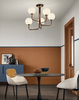 A dining room with orange walls and chairs featuring decorative Masiero Tee Chandeliers for luxury lighting.