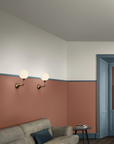 A living room with blue walls, a brown couch, and Masiero Tee Wall Sconce contemporary design.