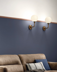 A living room with blue walls and a brown couch, adorned with Masiero Tee Wall Sconce for a touch of luxury lighting.