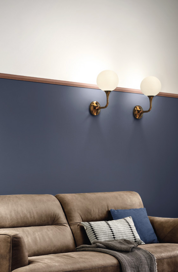 A living room with blue walls and a brown couch, adorned with Masiero Tee Wall Sconce for a touch of luxury lighting.
