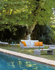 An outdoor living room with a pool and Sifas Basket Sofa Collection furniture featuring waterproof properties.