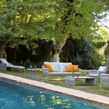 An outdoor living room with a pool and Sifas Basket Sofa Collection furniture featuring waterproof properties.