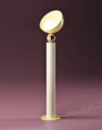 A versatile and vibrant lighting design from the Aurora Collection by Italamp featuring brushed gold accents, white glass diffuser, and retro-inspired finishes. A close up of a ivory finish floor lamp on a pink background