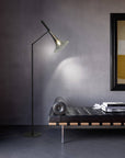 Baffo Collection by Italamp with conical design, titanium finish glass, and matching metal accents, showcasing Italian craftsmanship and elegance. A Baffo floor lamp in a black and titanium finish next to a leather ottoman in a luxury living room corner