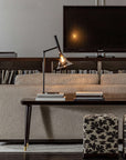 Baffo Collection by Italamp with conical design, titanium finish glass, and matching metal accents, showcasing Italian craftsmanship and elegance. A platinum finish baffo table lamp styled on books on a long table behind a sofa in a luxury living room