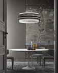A round chandelier installation in smoke and clear glass in above a round dining table in a modern theme interior of a luxury home. Discover the Carmen collection by Italamp – Italian Murano glass lighting in clear, smoke, and teak finishes. Elegant designs for luxurious interiors.