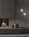 Colier collection by Italamp, featuring modular blown glass elements in vibrant colours and shapes, designed by Marc Sadler to create magical lighting effects. Set on a dark theme interior on the wall next to a fireplace and art objects