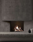Colier collection by Italamp, featuring modular blown glass elements in vibrant colours and shapes, designed by Marc Sadler to create magical lighting effects. A pair of wall sconce on a grey theme interiors on the 2 sides of a fireplace and some art object on a grey stone ledge.